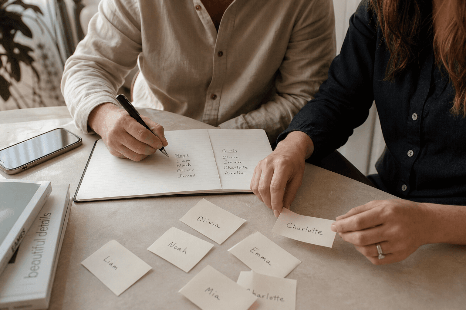 Hands comparing baby name cards and pressure-testing a shortlist.